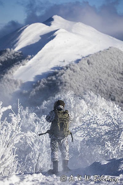 Zima, fotograf przyrody w stroju maskującym na rakietach śnieżnych