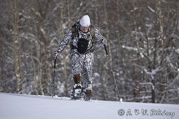 Zima, fotograf przyrody w stroju maskującym na rakietach śnieżnych