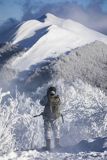 Zima, fotograf przyrody w stroju maskującym na rakietach śnieżnych