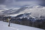 Zima, fotograf przyrody w stroju maskującym na rakietach śnieżnych