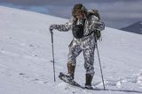 Zima, fotograf przyrody w stroju maskującym na rakietach śnieżnych
