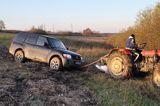 samochód terenowy zakopany w błocie, fachowa pomoc traktora niezbędna